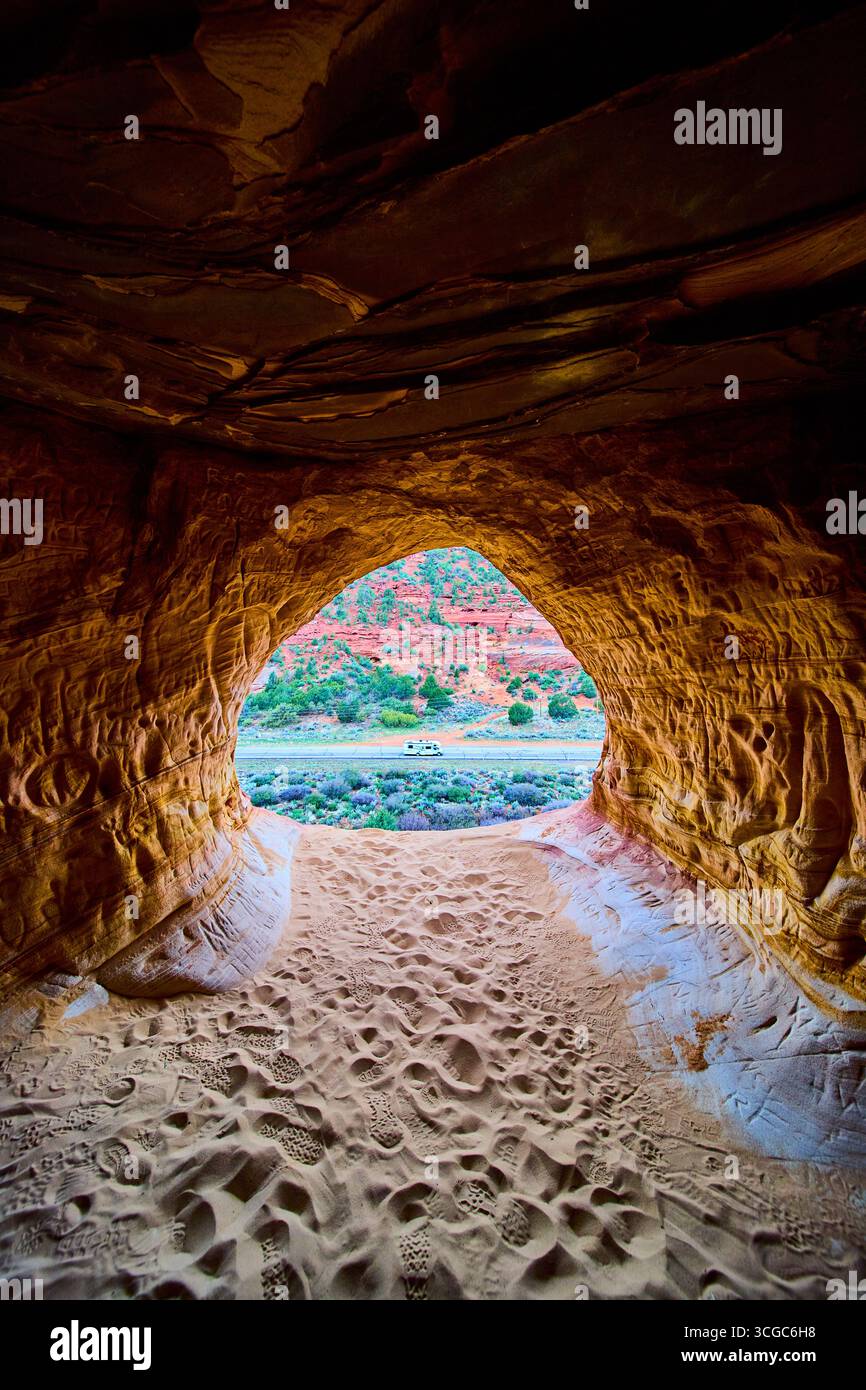 Interno della grotta di arenaria con impronte che si affacciano su Desert Hills e RV Utah Foto Stock