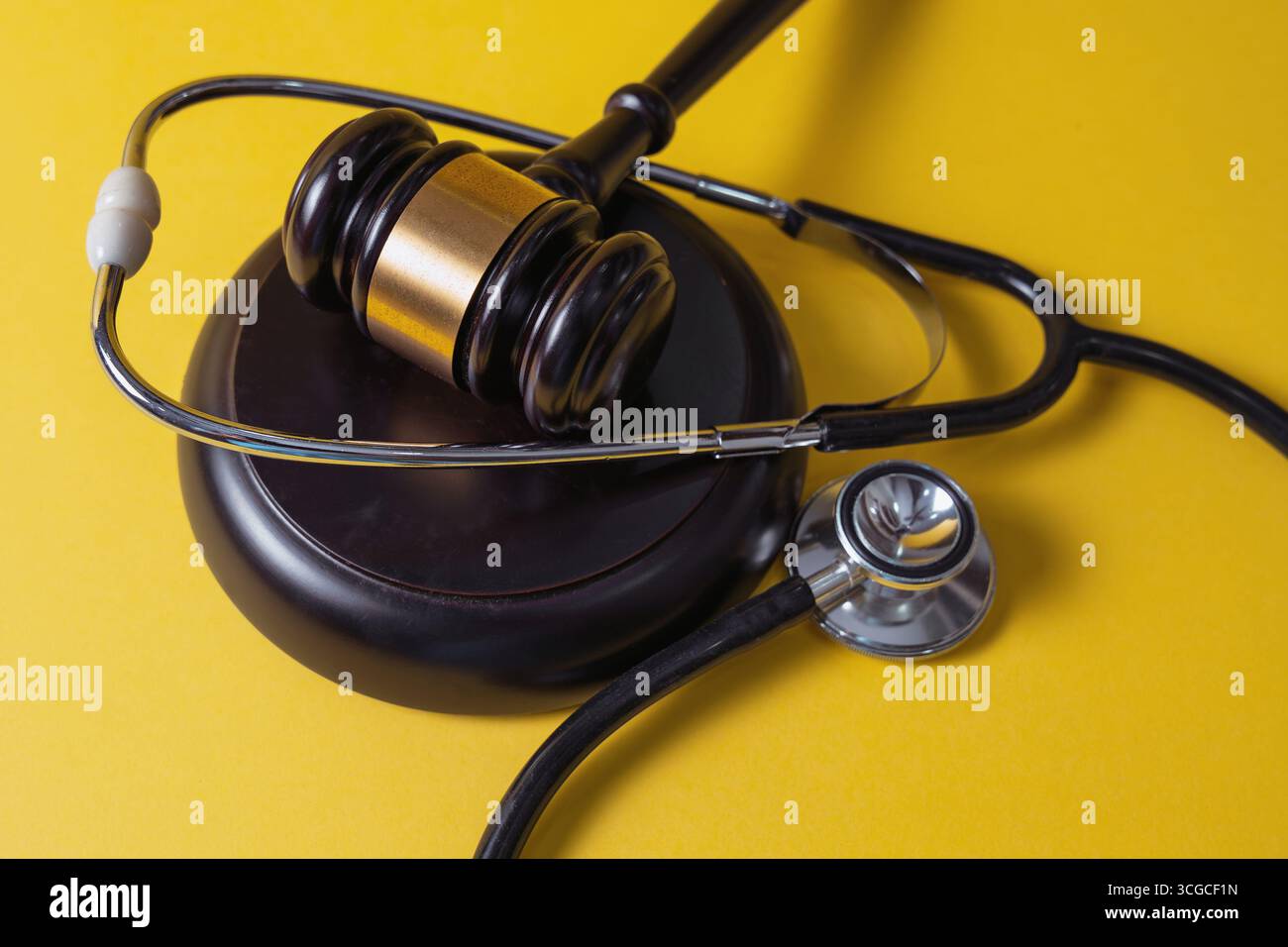 Martelletto con stetoscopio su sfondo giallo. Legale e medica. Foto Stock