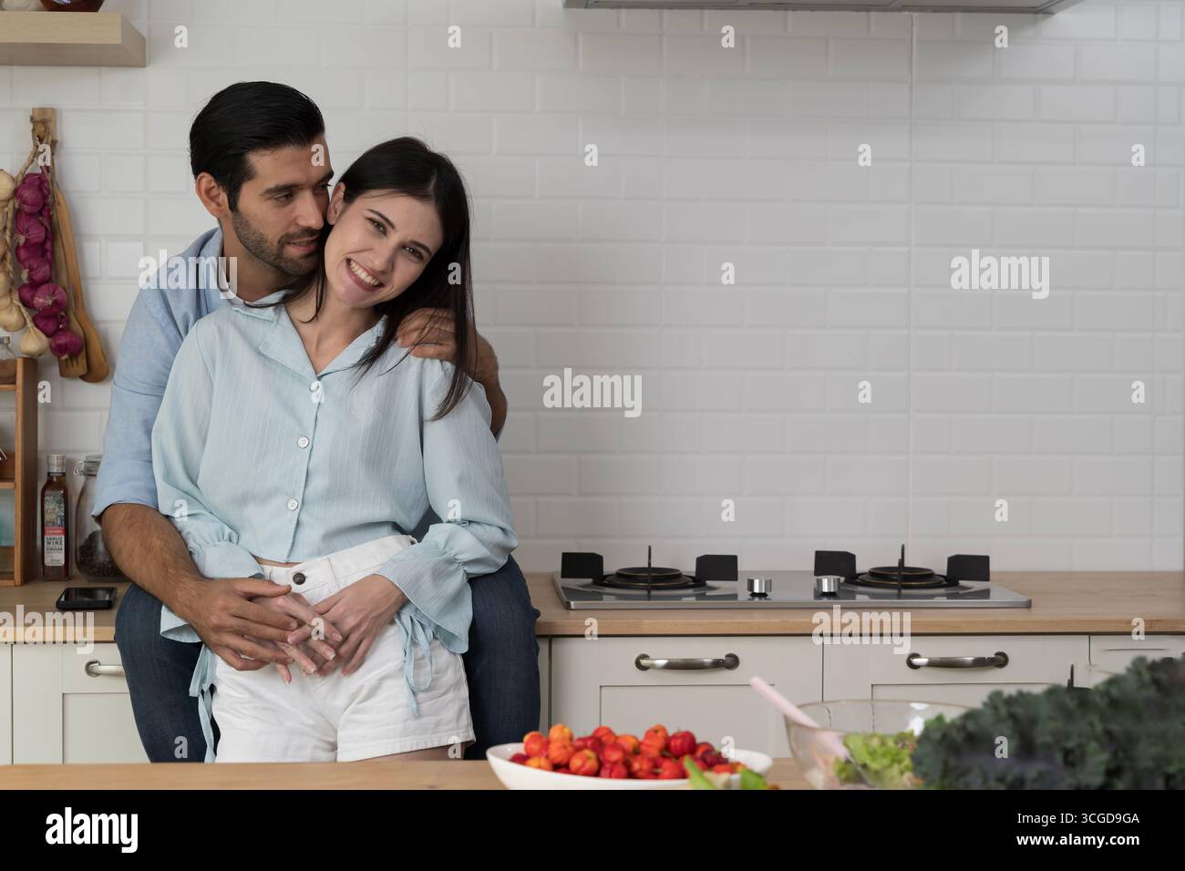 Felice coppia romantica abbracciando in cucina moderna, simboleggiando l'amore, legame familiare, stile di vita sano, cibo biologico, emozioni brillanti, insieme, a Foto Stock