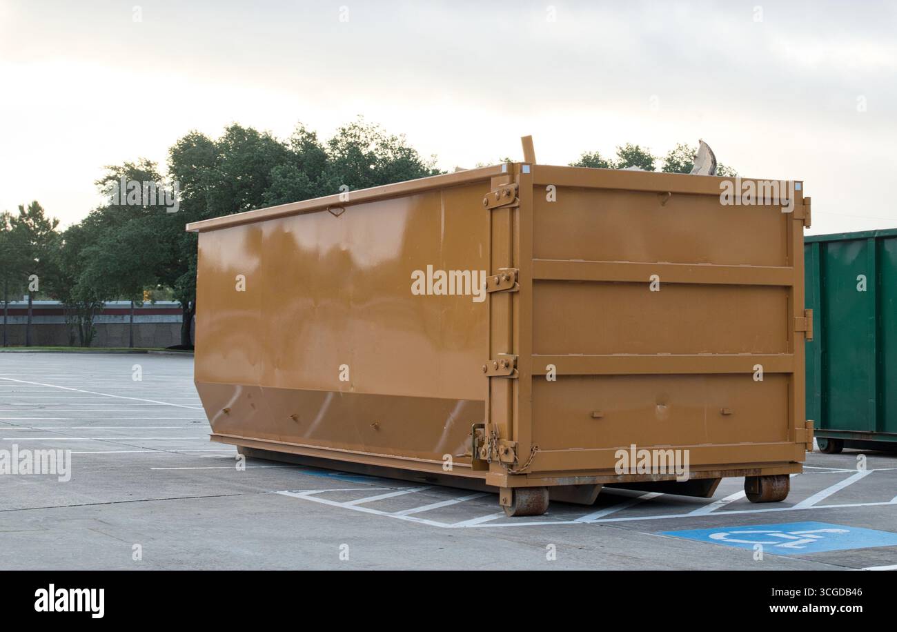 Cestino industriale per il noleggio di cassoni ribaltabili in un parcheggio commerciale, salta per la rimozione dei rifiuti marrone. Foto Stock