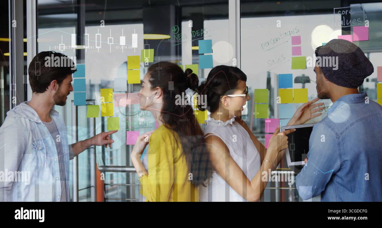 Collaborazione di un team di quattro persone che esaminano le idee sulla partizione in vetro in un ufficio aperto, con appunti adesivi Foto Stock