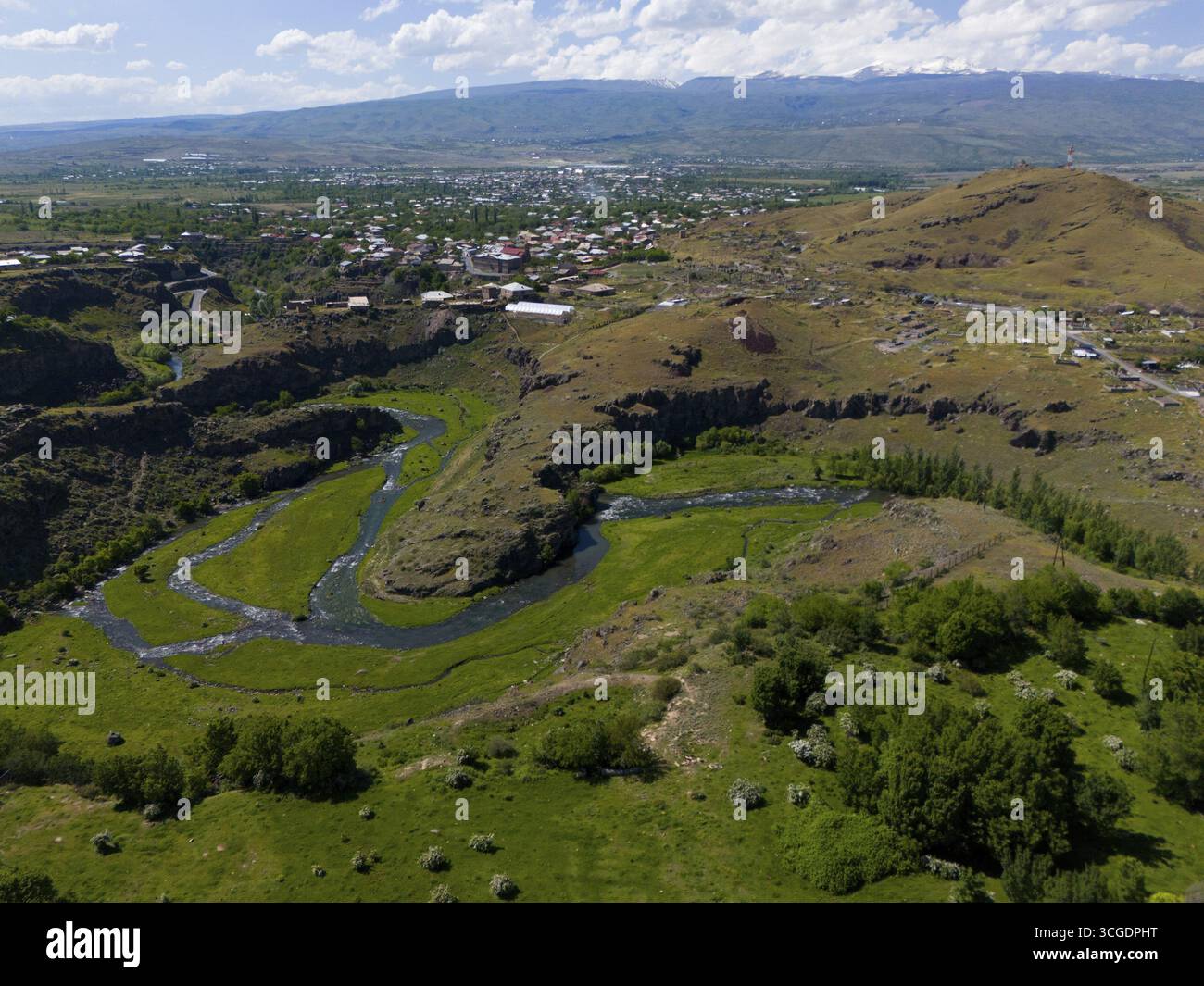 Fiume che scorre attraverso un paesaggio collinare con una città sullo sfondo sotto un cielo blu, vista aerea, fiume Kassagh, Oskahan, Oshakan, Takan, Aragaz Foto Stock