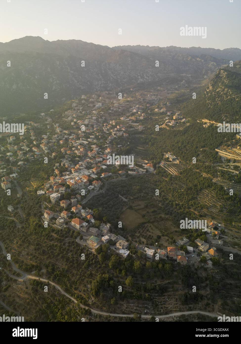 Veduta aerea di una piccola cittadina annidata tra colline ondulate con il sole che getta ombre tenui, Douma, Governatorato del Nord, Libano. Foto Stock