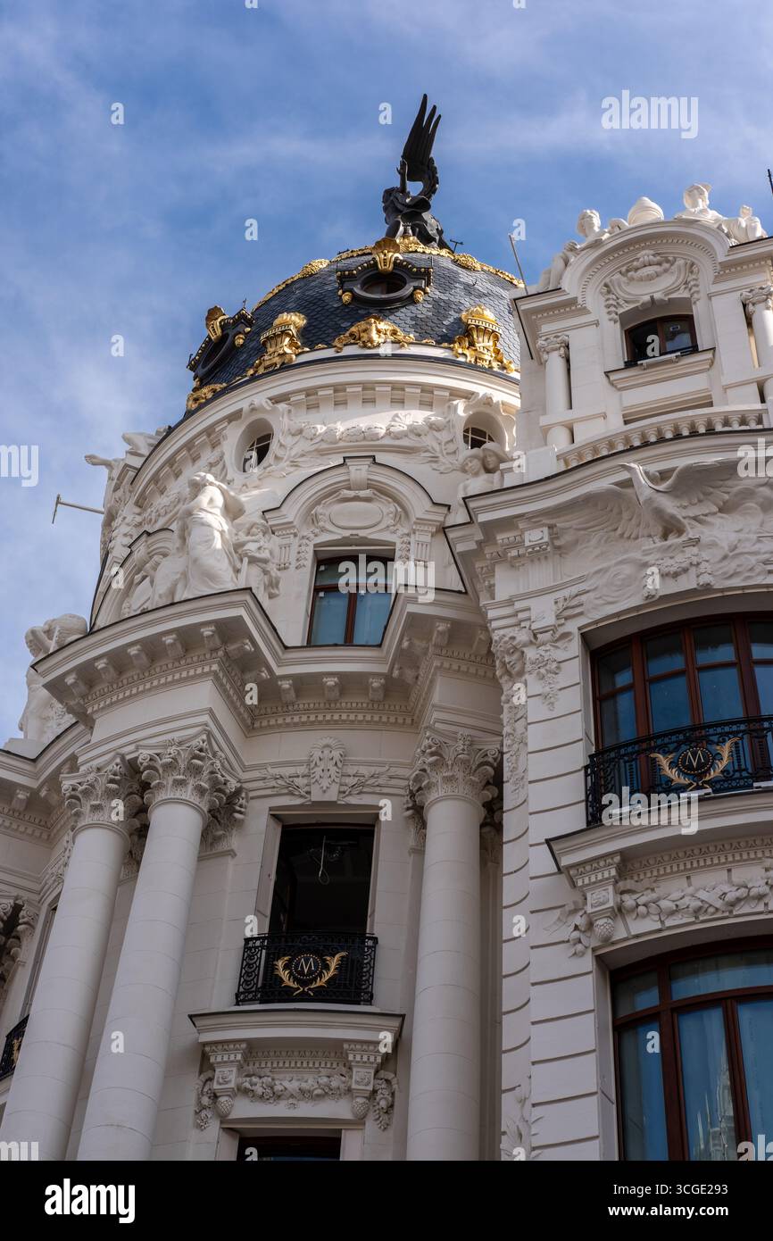 Vista della facciata ornata del Metropolis Building, la sua pietra bianca che contrasta con il cielo blu, incorniciata da intricati dettagli architettonici, Madrid, Spagna. Foto Stock