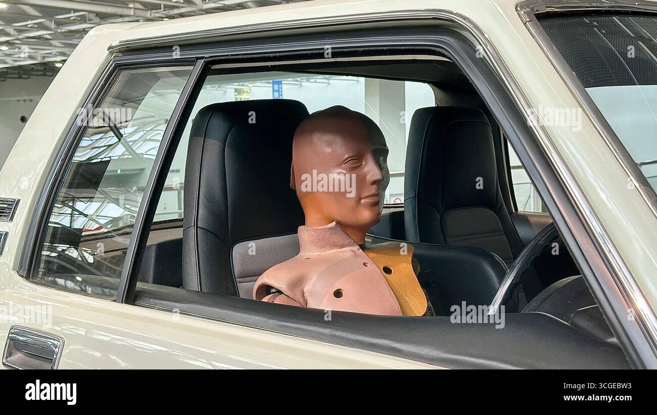 Un manichino per il crash test siede sul sedile del passeggero di un'auto bianca d'epoca, simulando un esperimento di sicurezza. Foto Stock