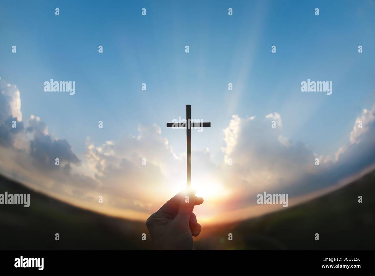 Una mano che tiene la croce di Gesù Cristo verso il sole nascente, uno sfondo di fede, speranza e il nuovo anno. Foto Stock