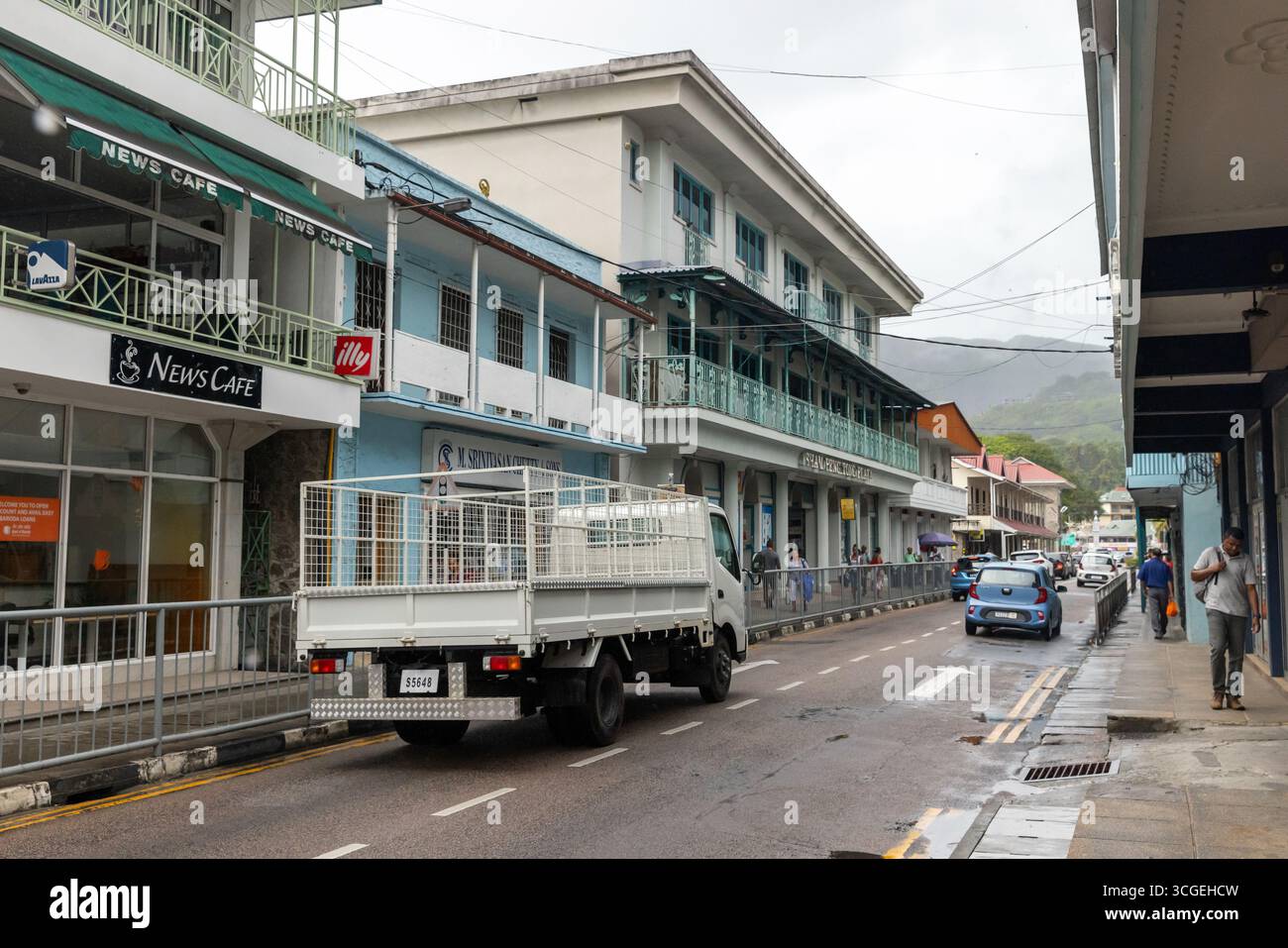 Victoria, Seychelles - 7 agosto 2023: Strada urbana con negozi, camion, auto e pedoni, che riflette l'attività quotidiana e i trasporti Foto Stock