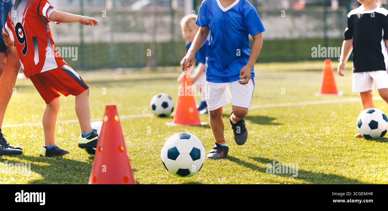 Allenamento di calcio per bambini con coni. Esercitazioni giovanili di calcio, controllo palla e pratica di agilità per bambini sul Grass Field Foto Stock