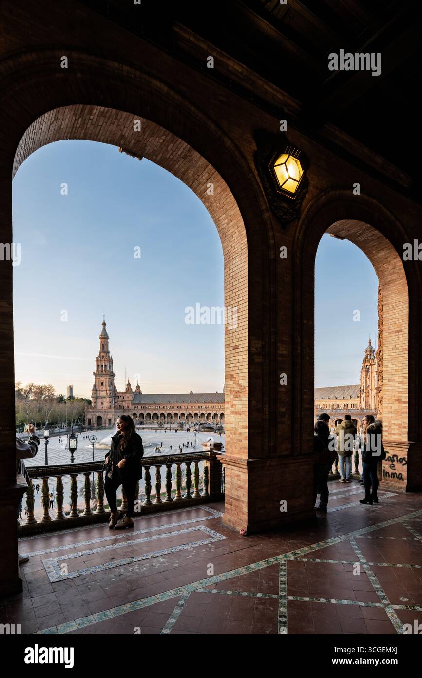 I visitatori si riuniscono sul balcone di Plaza de Espana a Siviglia, godendosi la luce del tardo pomeriggio e la splendida architettura incorniciata da archi. Foto Stock
