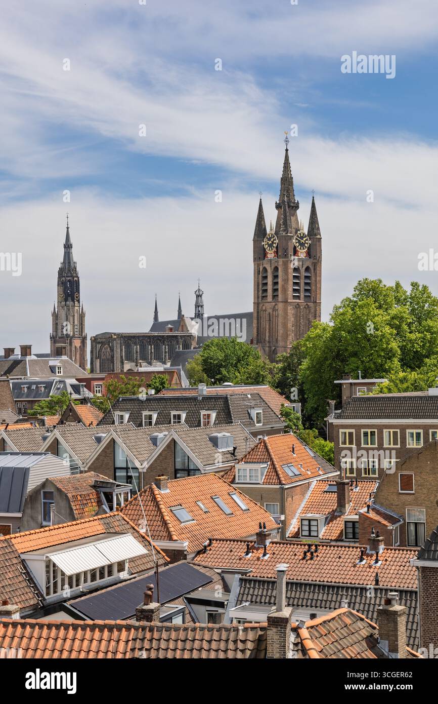 Accattivante vista aerea del paesaggio storico di Delft, con le iconiche chiese Vecchia e nuova che si innalzano sopra gli affascinanti tetti tradizionali sotto il blu Foto Stock