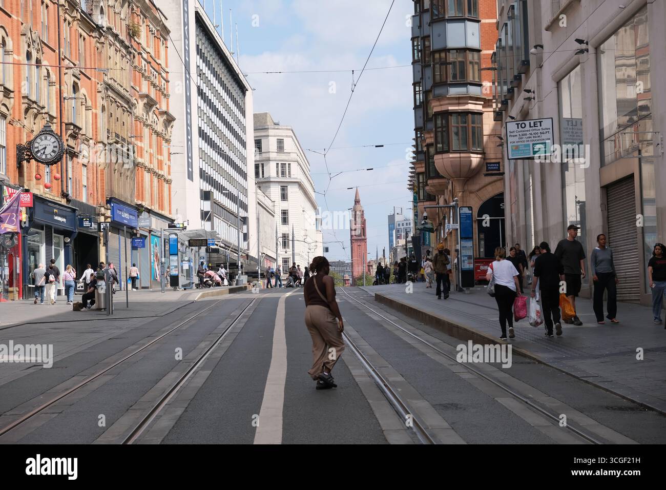 Woman attraversa i binari del tram su Corporation Street nel centro di Birmingham Foto Stock