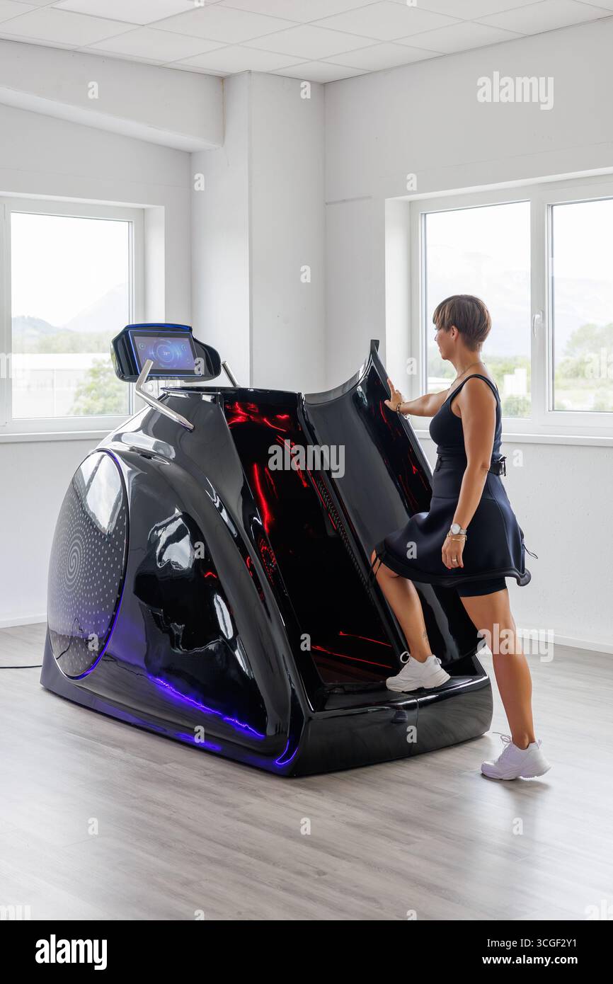 Donna dai capelli corti marroni che entra in un'innovativa capsula da tapis roulant sottovuoto con riscaldamento a infrarossi per allenamento cardio, dimagrimento e cura della pelle Foto Stock