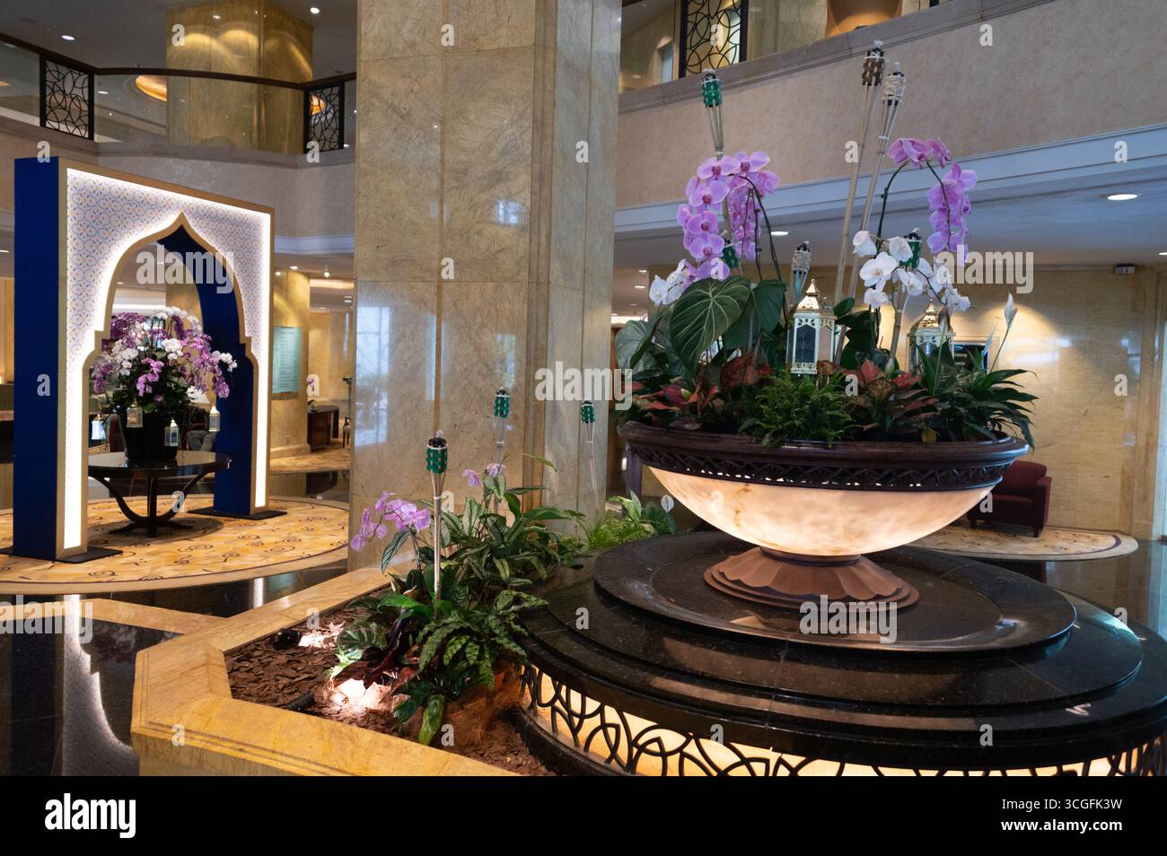 Nel foyer principale di un hotel a cinque stelle a Kuala Lumpur, Malesia, che mostra disegni islamici come il grande arco e una grande mostra di flora. blu Foto Stock