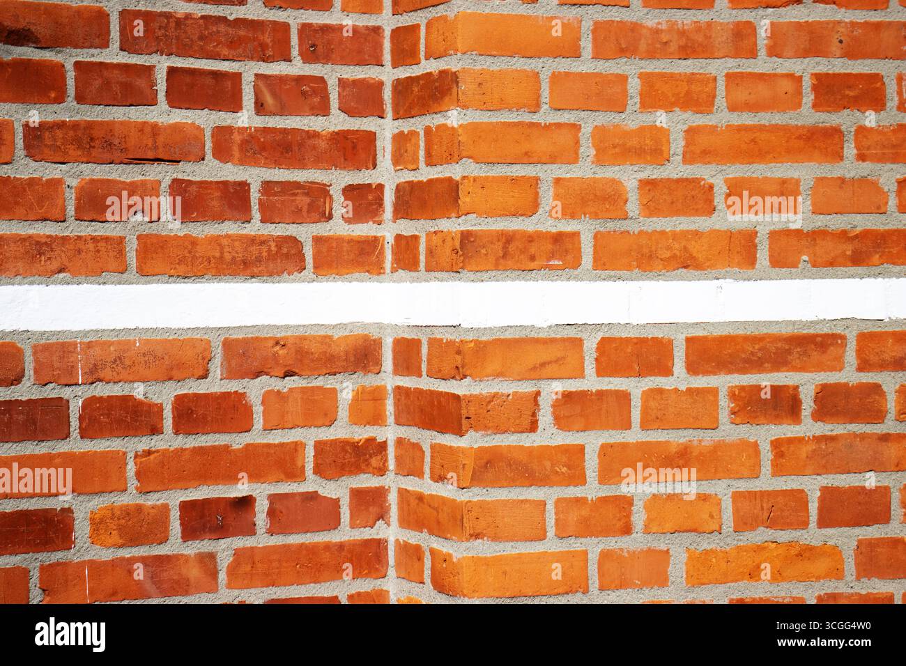 primo piano di una parete di mattoni rossi con una linea spessa o una fascia di cemento verniciata di bianco Foto Stock