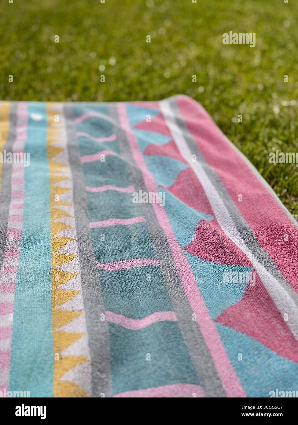 Asciugamano colorato appeso sull'erba in un parco in una giornata di sole. Foto Stock