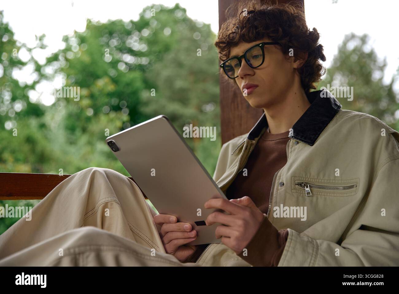Bel giovane che fa una passeggiata tranquilla mentre si immerge nei contenuti digitali della natura. Foto Stock