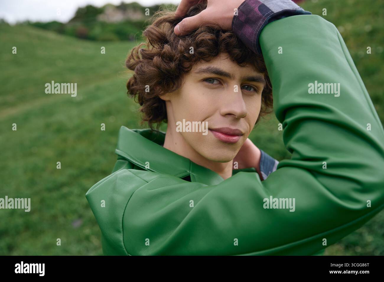 Il giovane fa una passeggiata in un paesaggio verde vivace, immergendosi nella serena atmosfera all'aperto. Foto Stock
