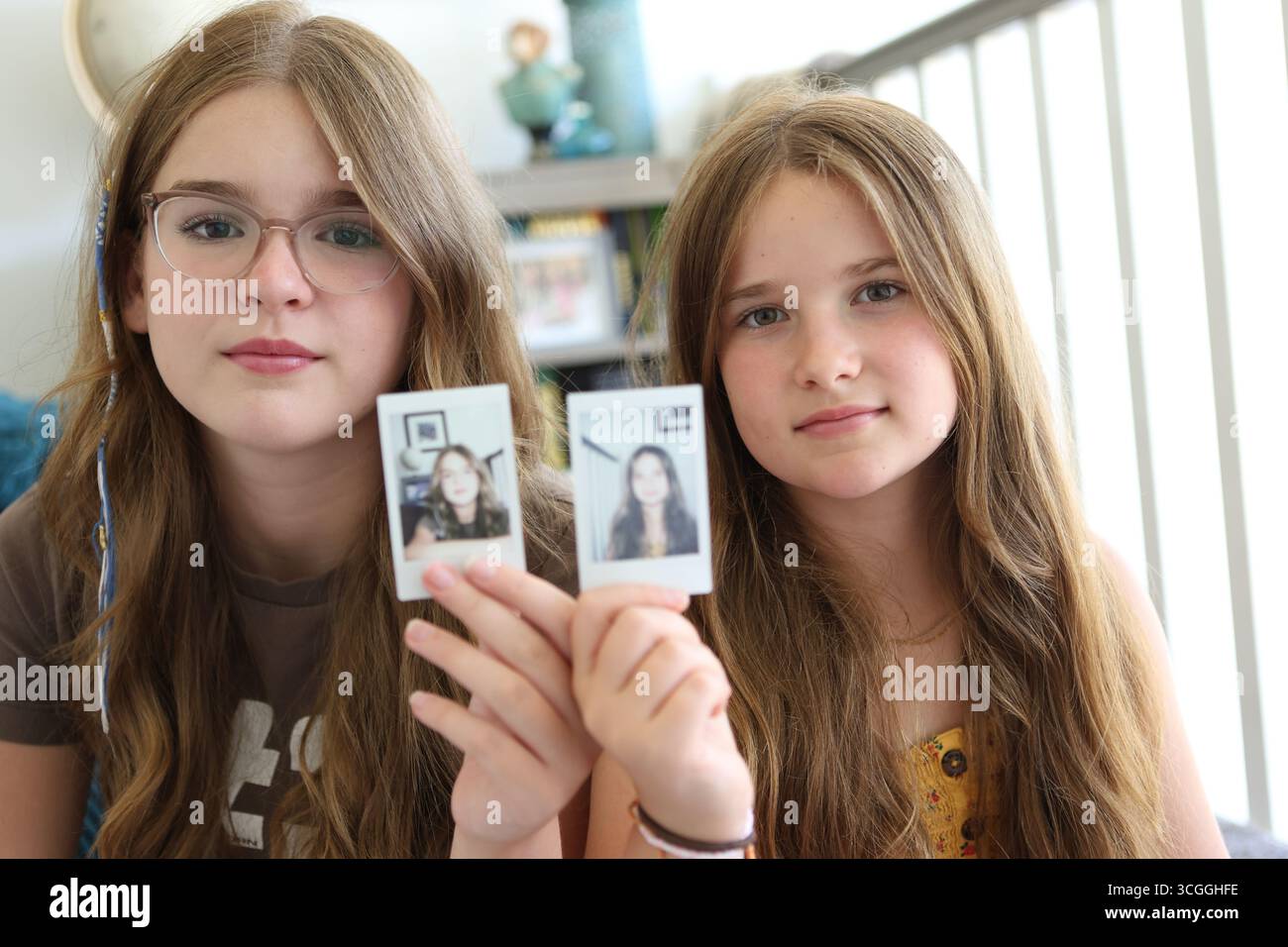 Due ragazze tengono in mano la stampa di se stesse scattate con il concetto di fotocamera istantanea l'identità l'aspetto delle sorelle Foto Stock