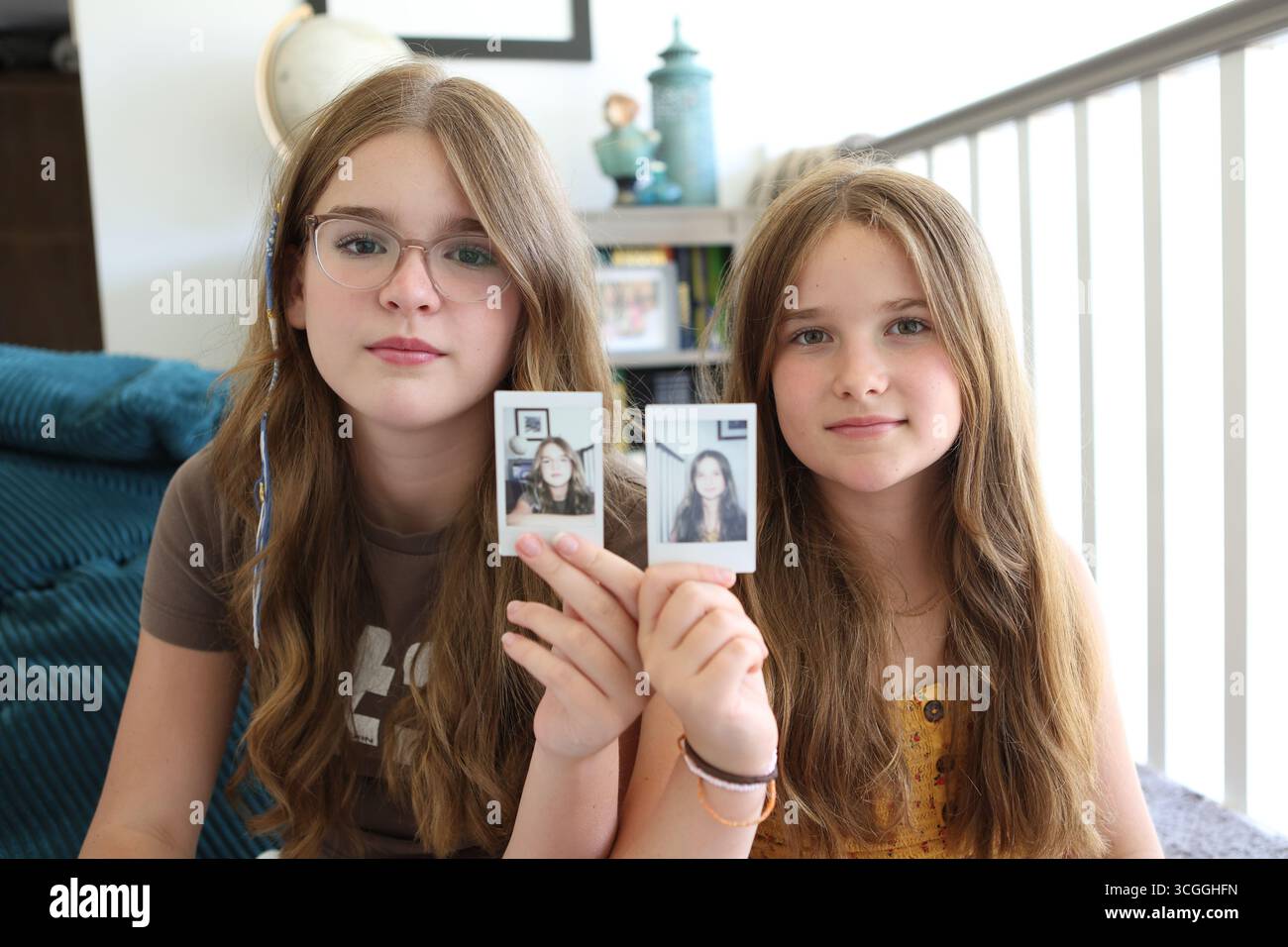 Due ragazze tengono in mano la stampa di se stesse scattate con il concetto di fotocamera istantanea l'identità l'aspetto delle sorelle Foto Stock
