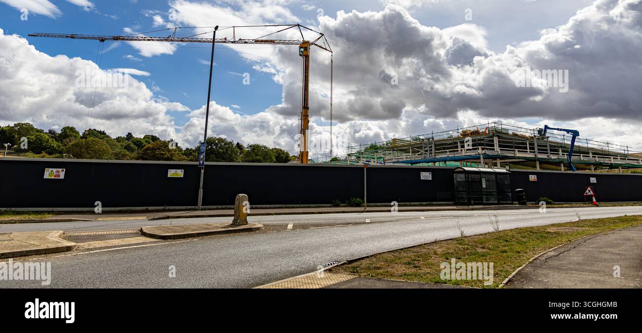 Cantiere del nuovo negozio Lidl a Calne Wiltshire con gru alta e ponteggi addossati a un cielo blu nuvoloso dietro una recinzione nera agosto 25 Foto Stock