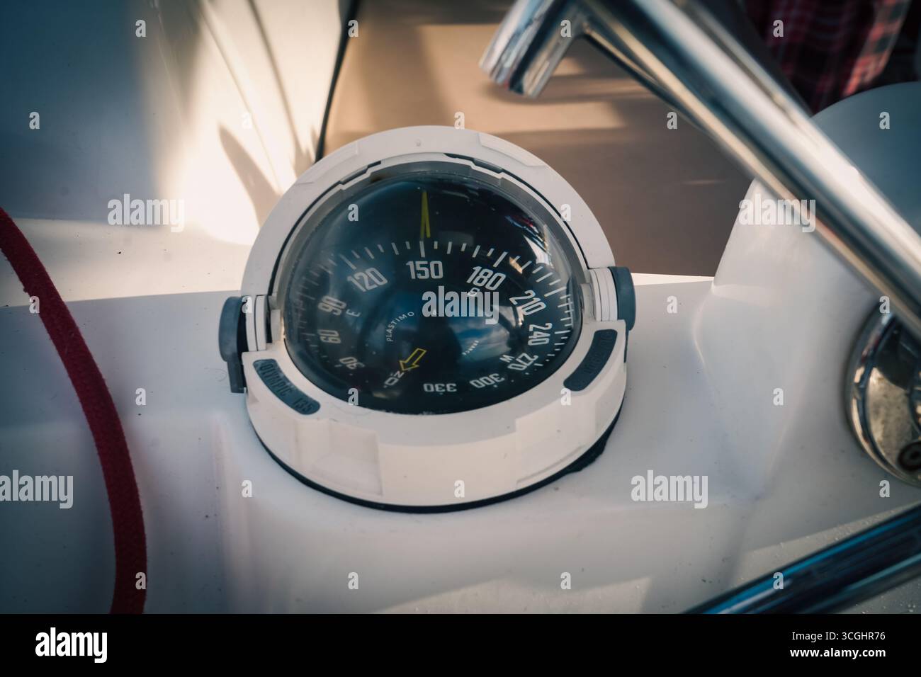Bussola binaria marina al timone di una barca a vela; cupola riflettente, alloggiamento bianco e guida in acciaio inox. Navigazione nautica in primo piano alla luce del giorno, nessuna gente. Foto Stock