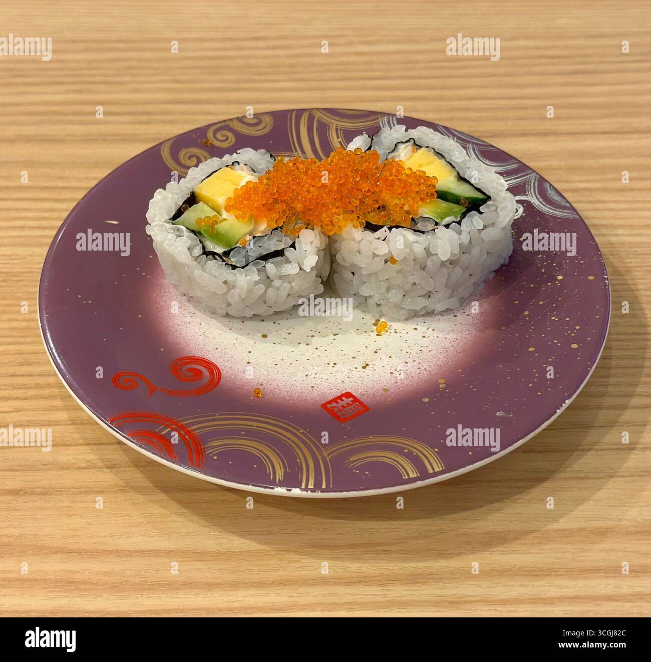 Rotolo di sushi uramaki giapponese con bastoncino di granchio, avocado, cetrioli e tobiko Foto Stock