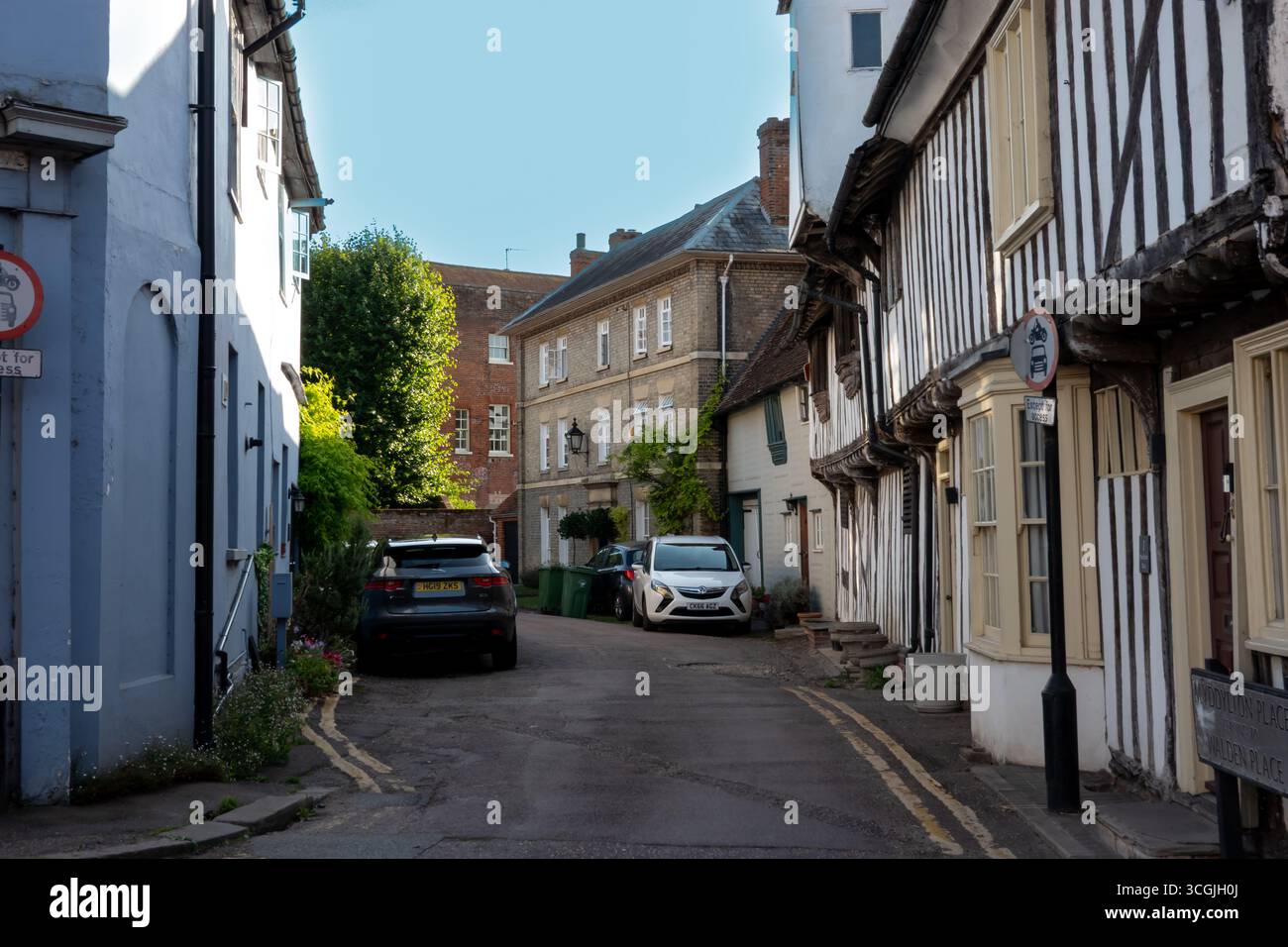 Una scena di strada a Saffron Walden, Essex, Inghilterra, con edifici storici e auto parcheggiate sotto un cielo limpido. Foto Stock
