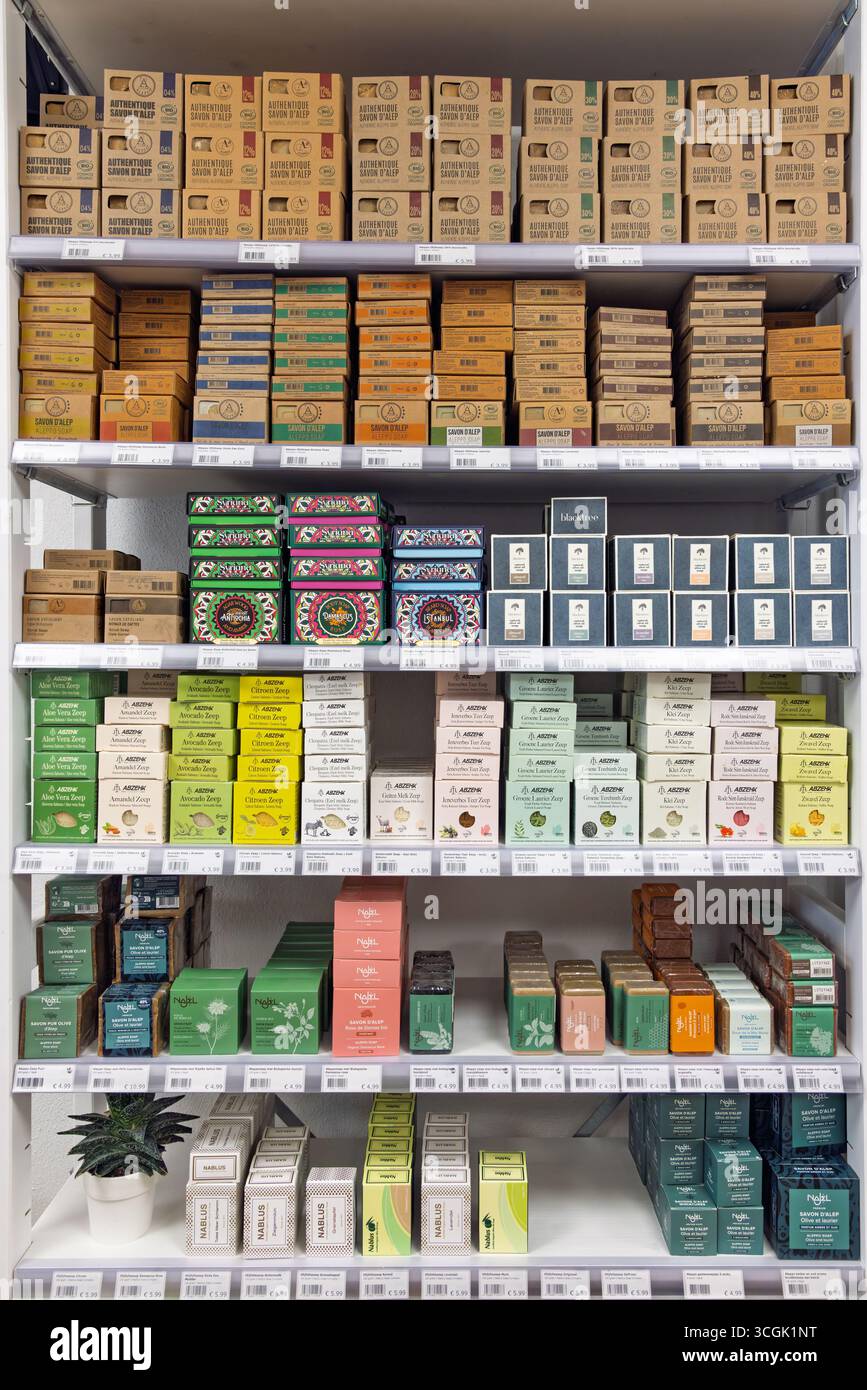 Un'esposizione ben fornita di varie saponette confezionate su scaffali bianchi in un punto vendita. I prodotti sono caratterizzati da diversi design, colori e marchi Foto Stock
