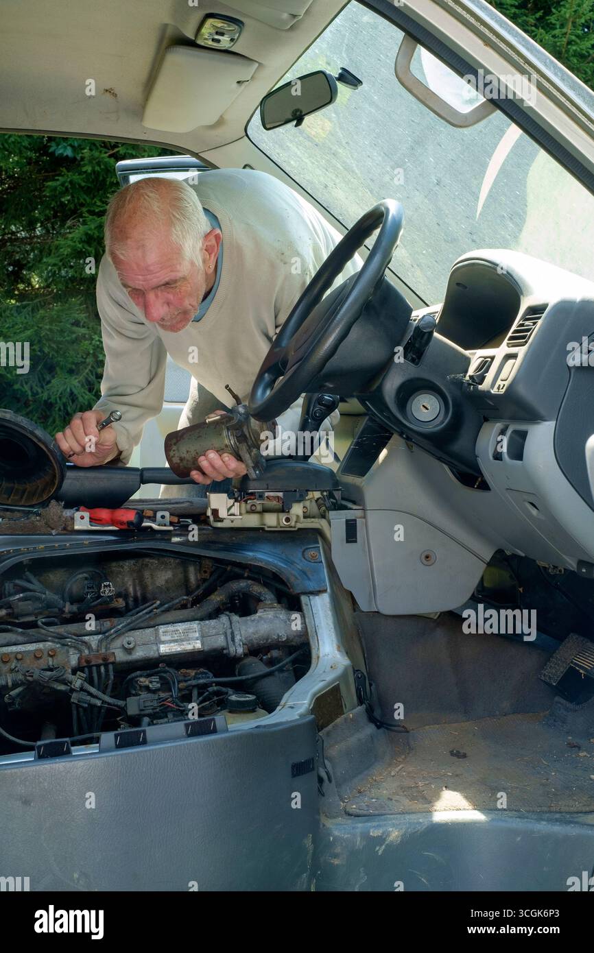 uomo più anziano che rimuove il filtro del gasolio dal motore mazda bongo friendee per la sostituzione Foto Stock