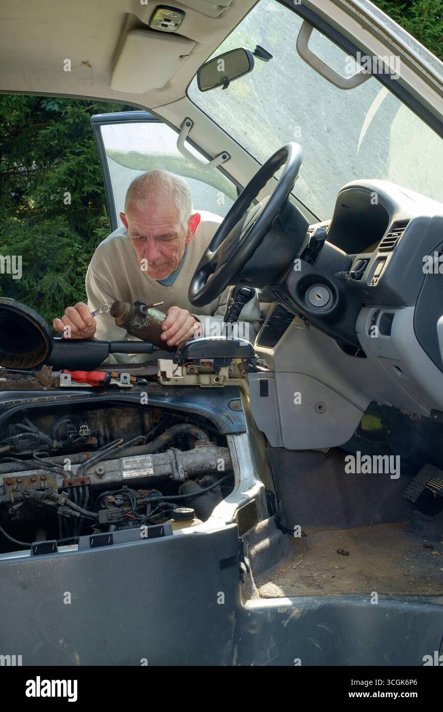 uomo più anziano che rimuove il filtro del gasolio dal motore mazda bongo friendee per la sostituzione Foto Stock