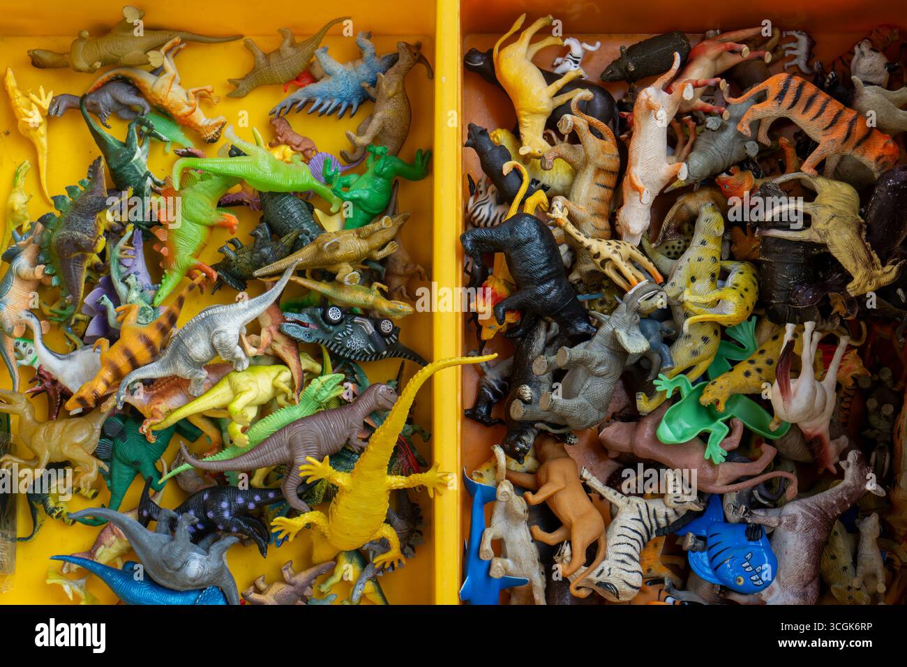 Ipoh, Malesia - 17 agosto 2025: Una foto in alto che mostra una varietà di animali in plastica e figure di dinosauro in miniatura impilati insieme in un bidone giallo A. Foto Stock