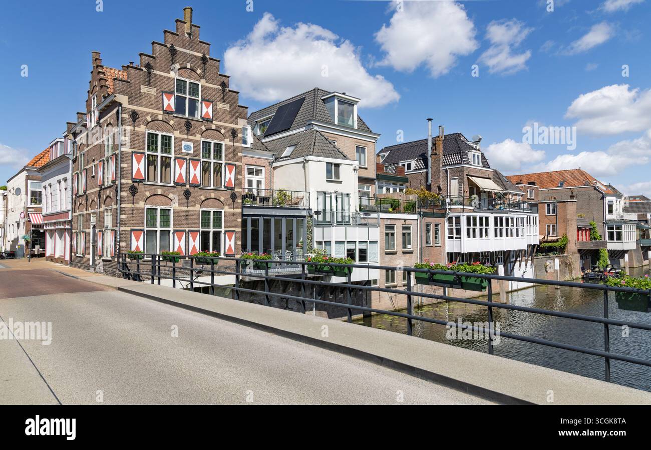 Affascinanti case olandesi tradizionali fiancheggiano lo storico canale di Gorinchem, adornate da balconi e acque riflettenti, sotto un cielo blu luminoso. Foto Stock