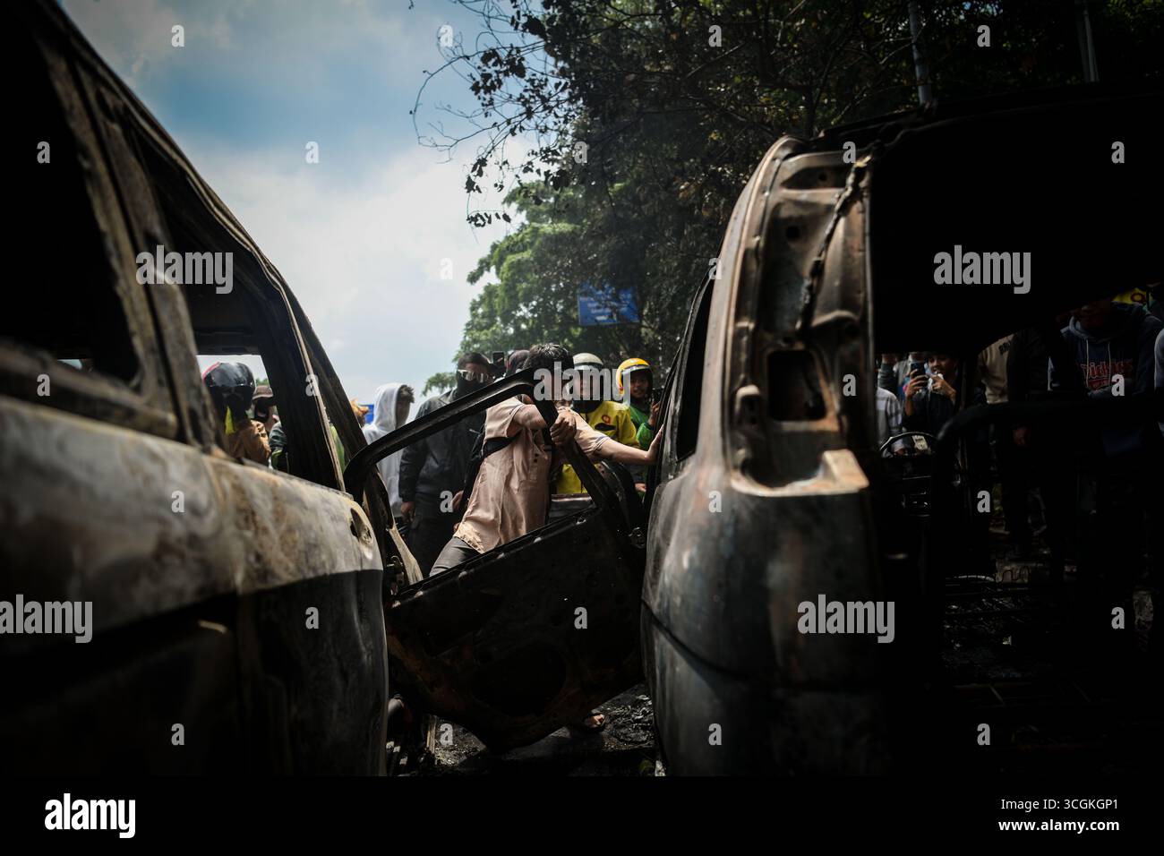 I residenti rimuovono parti di un'auto bruciata durante una protesta davanti al quartier generale della Mobile Brigade a Kwitang, nel centro di Giacarta, giovedì (28 agosto, Foto Stock