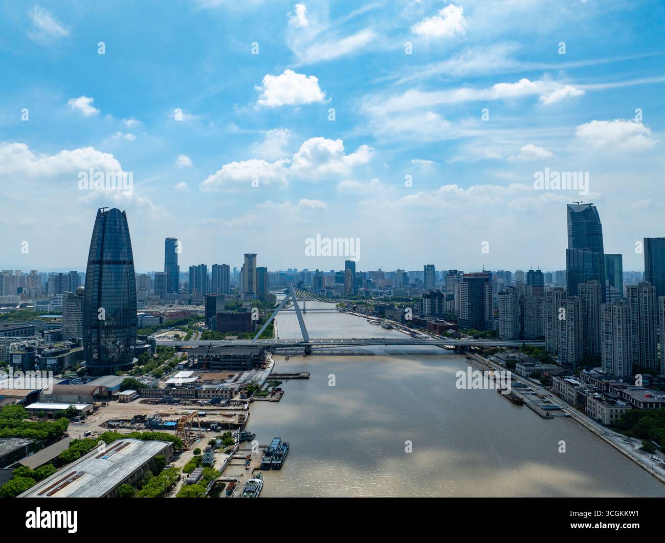Una vista aerea della città di Ningbo in Cina mostra edifici alti, un ampio fiume e un lungo ponte sotto un cielo blu brillante. Foto Stock