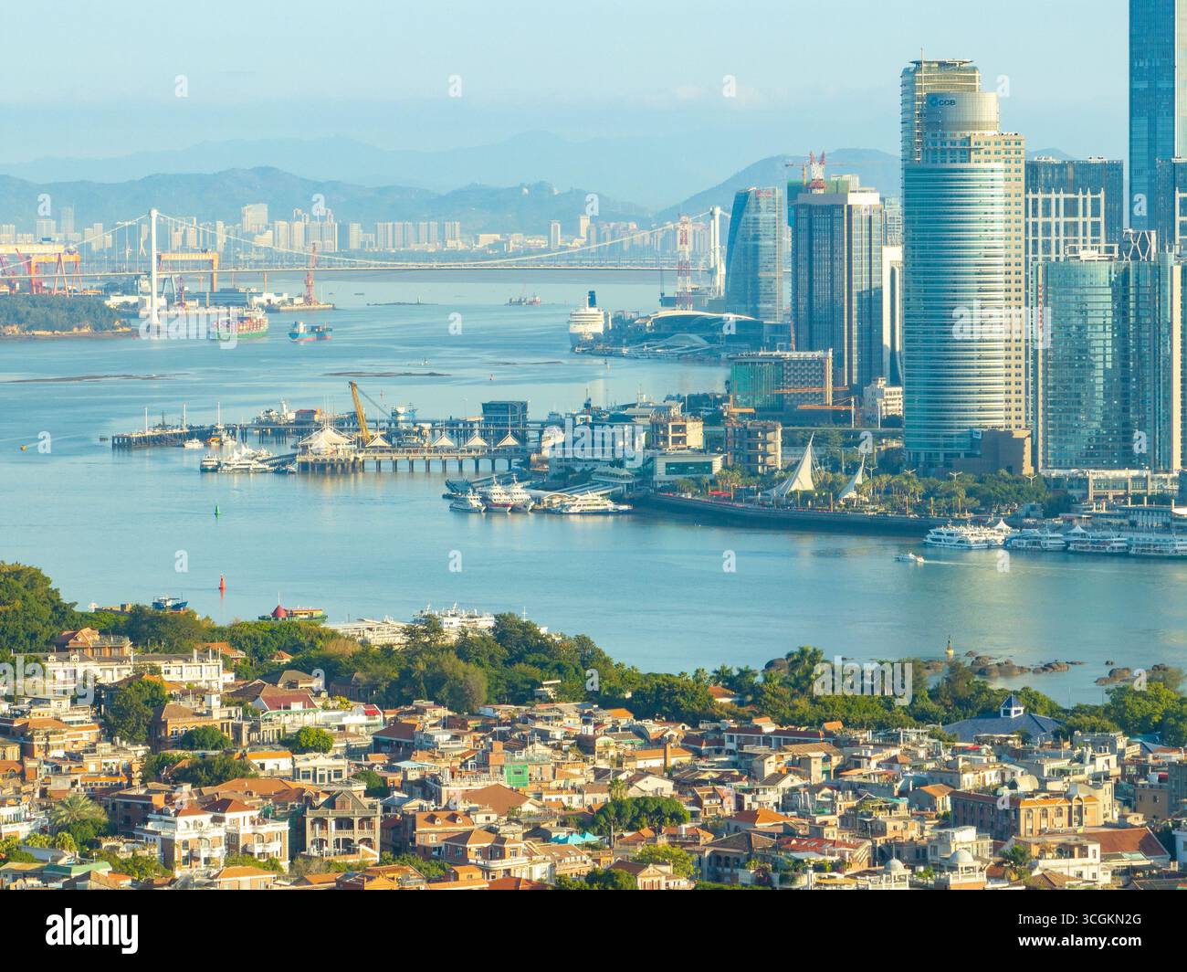 Xiamen, Cina, rivela il suo paesaggio urbano diversificato con alti grattacieli, operazioni portuali attive e affascinanti residenze antiche lungo la costa panoramica Foto Stock