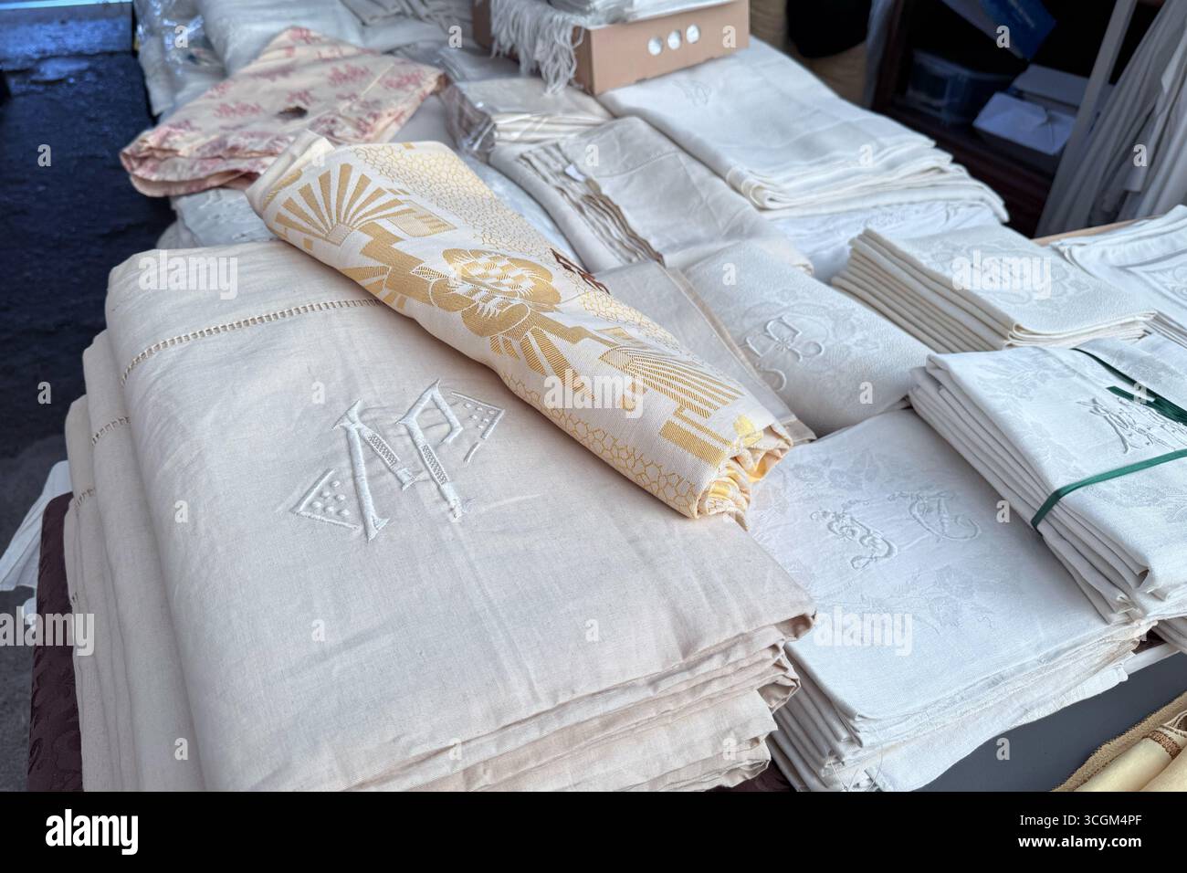 Pile di lenzuola vintage ricamate e fantasia esposte su un tavolo al mercato delle pulci. Mercato delle pulci, conservazione dei tessuti, tessuti monogrammati Foto Stock
