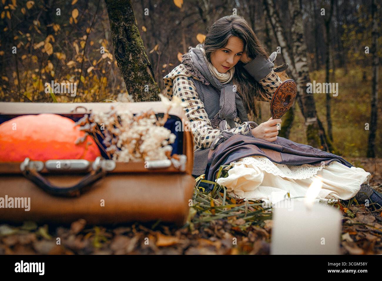 Una donna guarda allo specchio nella foresta autunnale Foto Stock