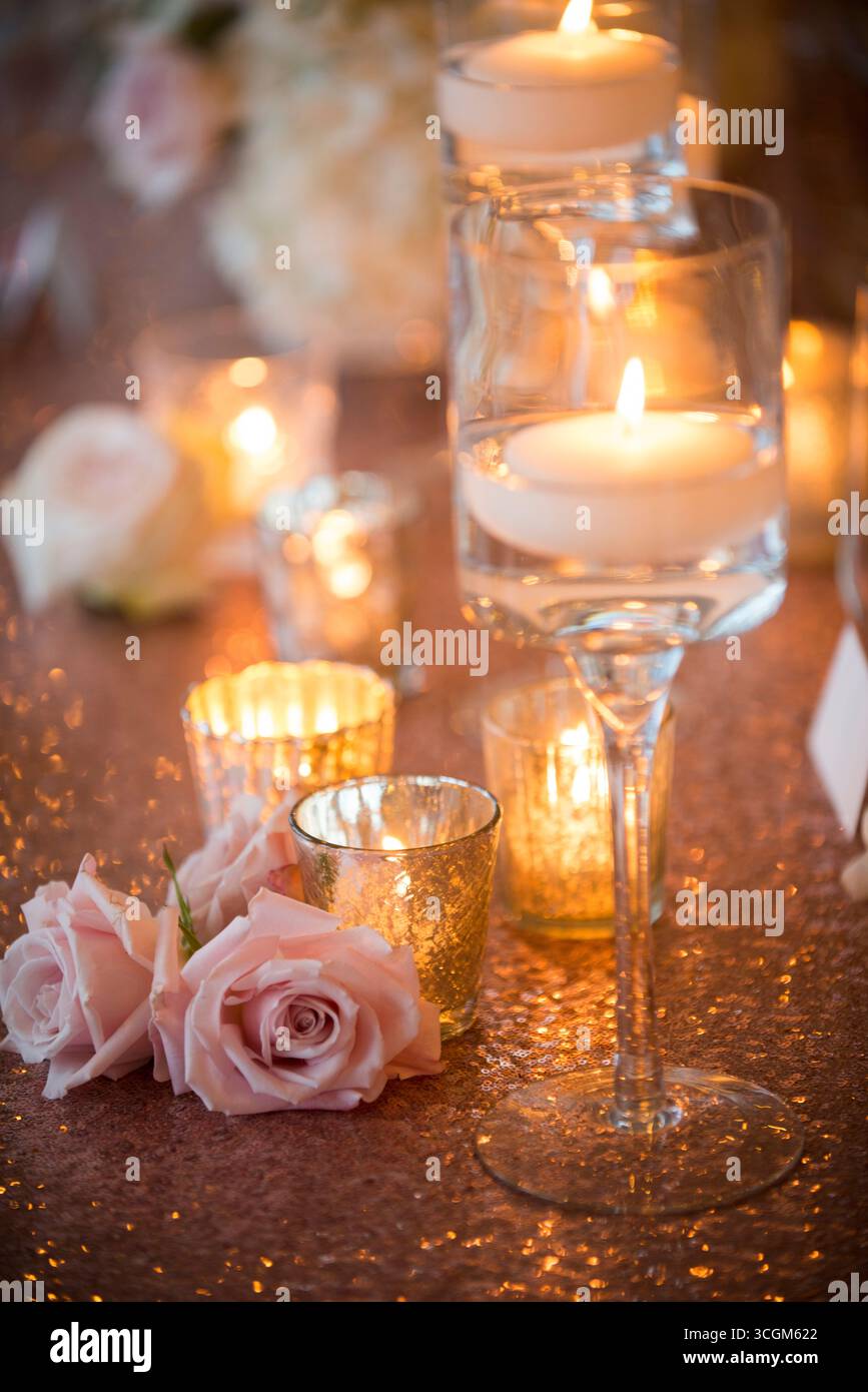 Rose rosa e candele galleggianti su un tavolo da sposa scintillante Foto Stock