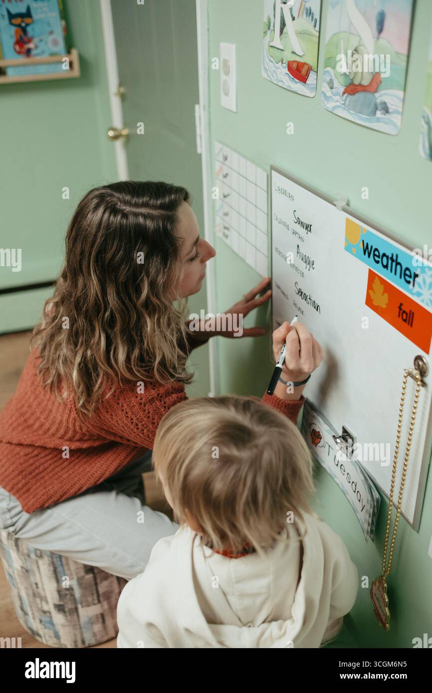Insegnante che scrive su lavagna bianca con studente in classe montessori Foto Stock