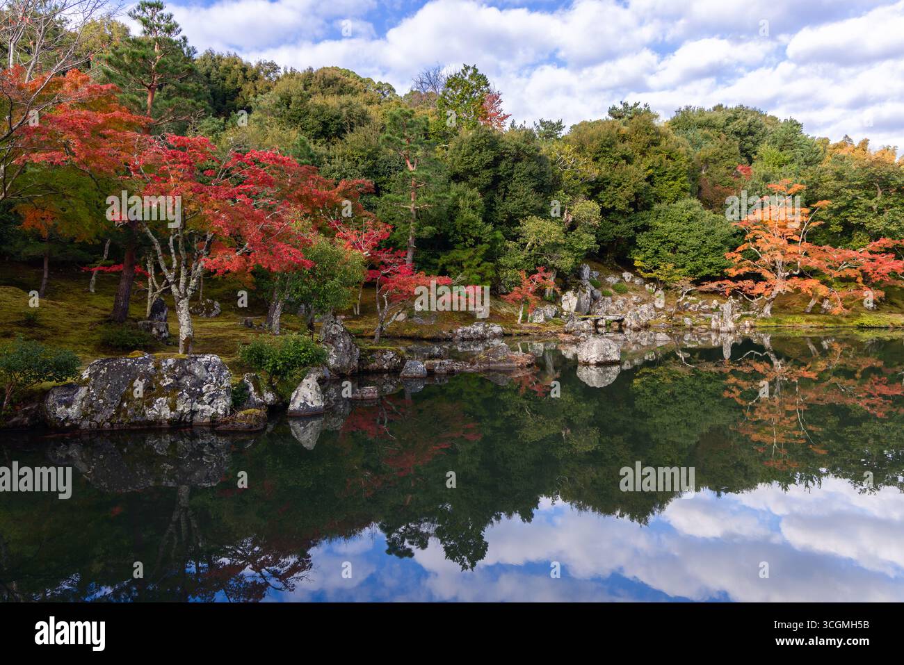 Immerso nel parco giapponese con fogliame e pietre ardenti che si riflettono nell'acqua, incarnano la bellezza stagionale e lo spirito tranquillo dello Zen in modo semplice Foto Stock