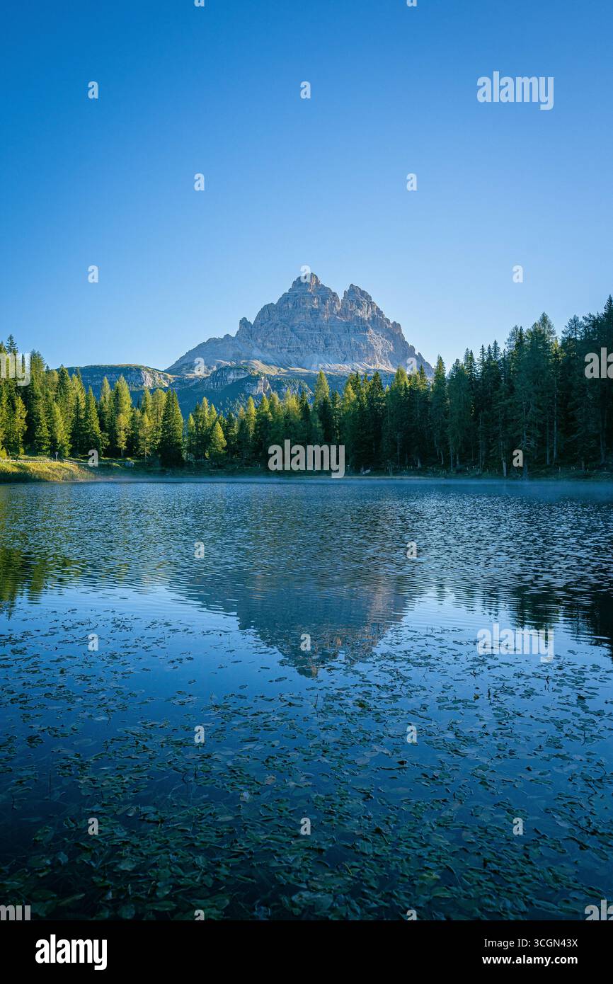 Lago Antorno in alto Adige con acque calme color smeraldo, foresta circostante e maestose vette delle tre Cime di Lavaredo nelle Dolomiti Foto Stock
