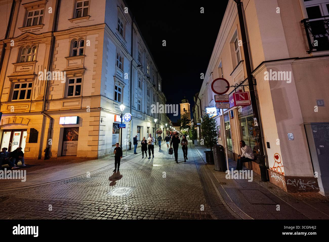 Rzeszow, Polonia - 22 agosto 2025: Vivace strada notturna a Rzeszow, Polonia, con edifici illuminati e pedoni. Foto Stock