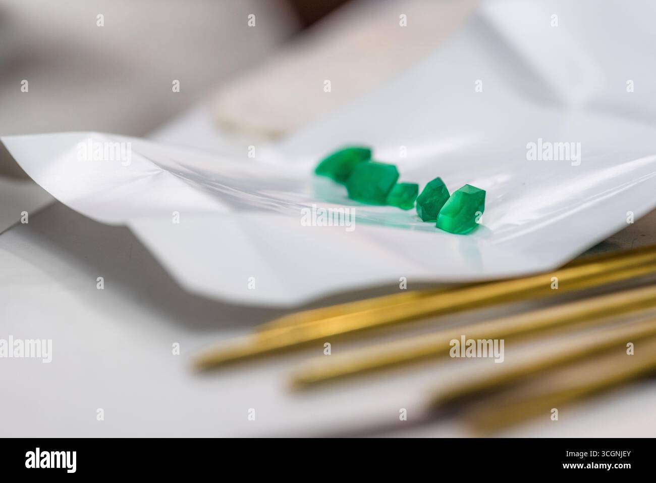 Gli smeraldi tagliati di precisione delle miniere di Muzo sono esposti su un sacchetto di carta appiattito in un laboratorio di taglio dello smeraldo a Bogotá, Colombia. Foto Stock