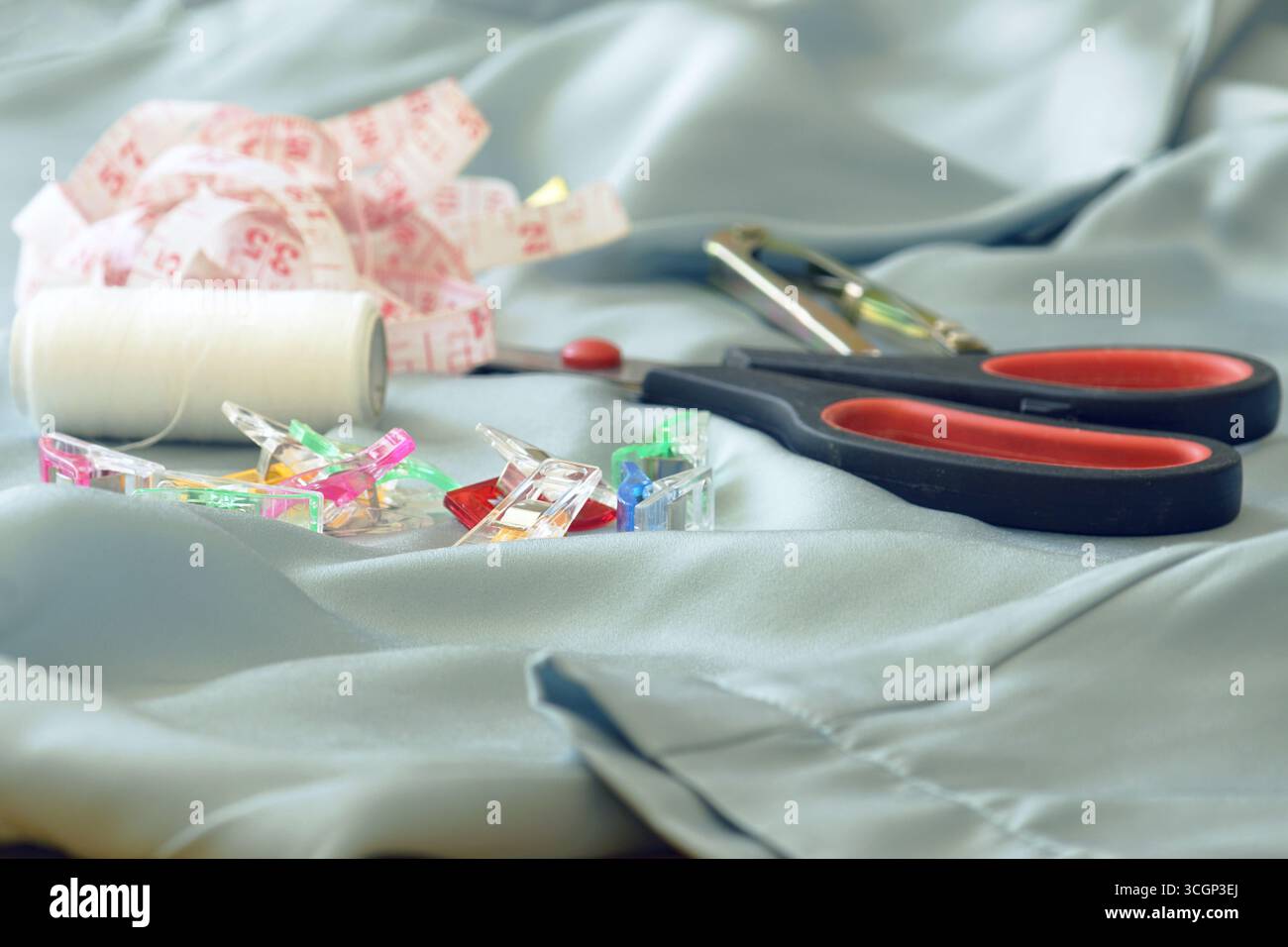 Attrezzature sartoriali su tessuto leggero che simboleggiano il consumo consapevole e la moda circolare. Riciclare vestiti vecchi, riciclare, progetti zero rifiuti Foto Stock
