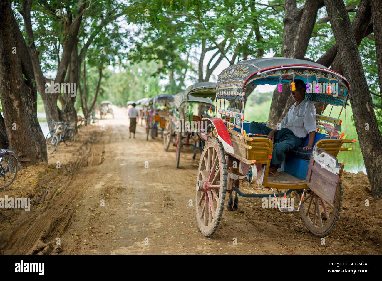 Trasporto turistico Inwa Horse and Carriage Amarapura Myanmar // INWA (noto anche come Ava), Myanmar - le corse in carrozza e a cavallo sono un mezzo di trasporto primario per i turisti che esplorano l'antica città di Inwa (nota anche come Ava). Questi tradizionali carretti a cavallo sono essenziali per navigare nel sito storico, poiché i veicoli moderni come taxi o auto hanno un accesso limitato. Inwa, un'ex capitale imperiale del Myanmar dal XIV al XIX secolo, è situata su un'isola formata dai fiumi Ayeyarwady (noto anche come Irrawaddy) e Myitnge. L'ampio sito archeologico è rinomato per la sua dispersione Foto Stock