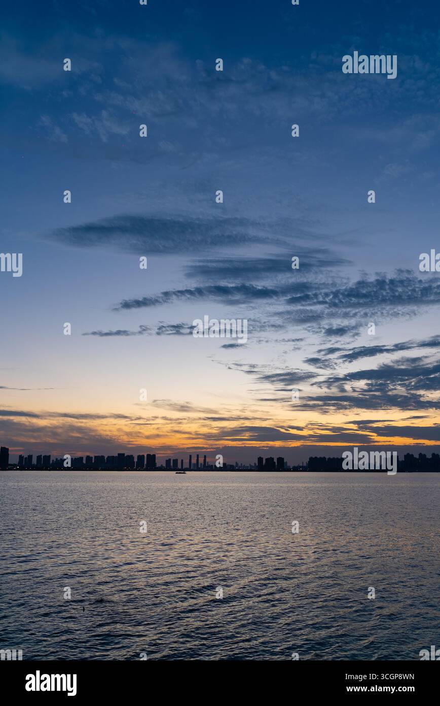 Il paesaggio del lago China Tangxun Jiangxia Wuhan mostra una tranquilla scena acquatica sotto un cielo colorato. Foto Stock