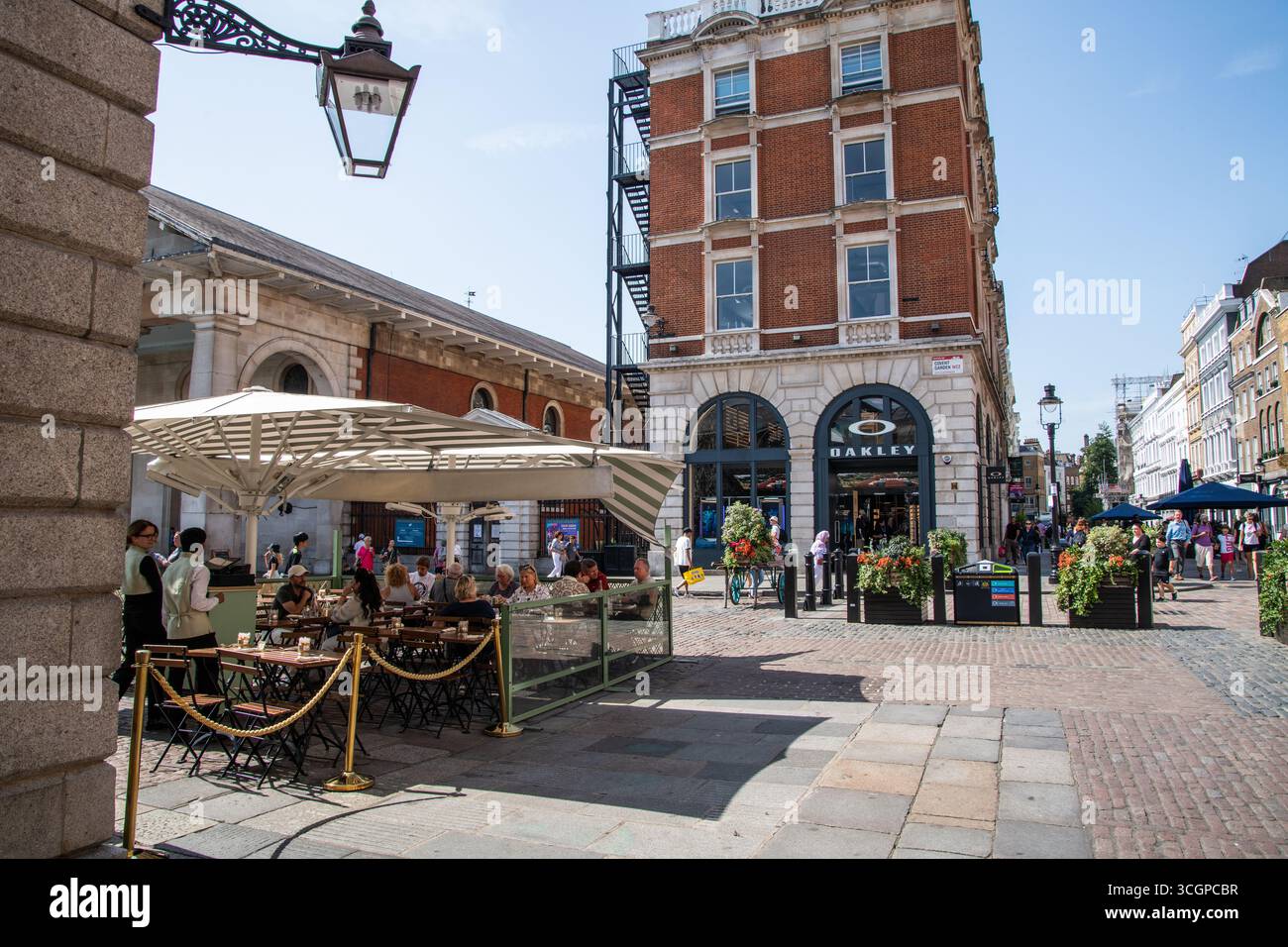Persone che cenano all'aperto al Covent Garden Market di Londra. Vivace scena con ristoranti, sole e atmosfera sociale nella storica piazza del mercato. Foto Stock
