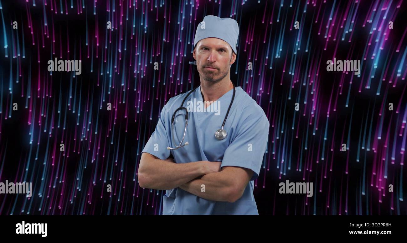 Medico in piedi che indossa scrub blu e berretto scrub in studio, con stetoscopio e strisce LED Foto Stock