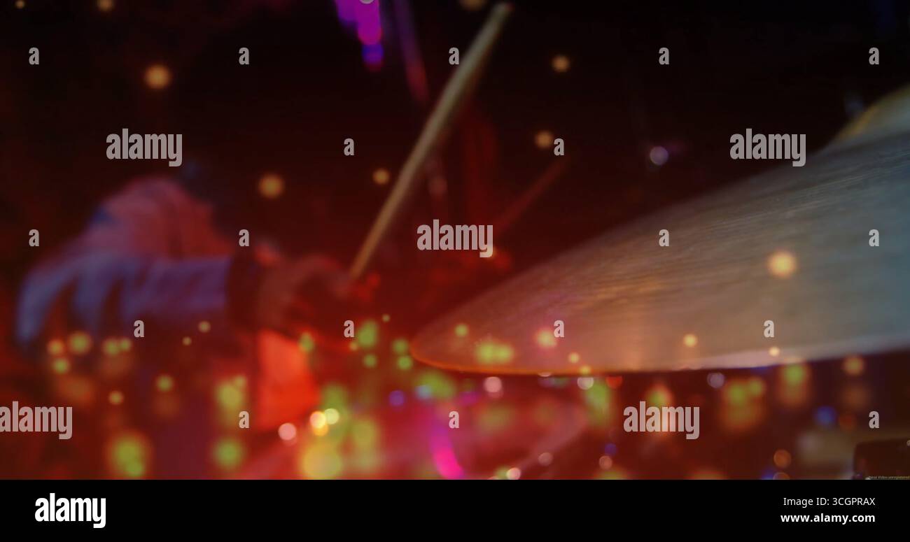 Batterista indiano che indossa una camicia che colpisce il piatto con la bacchetta sul palco poco illuminato, sotto le luci del palco Foto Stock