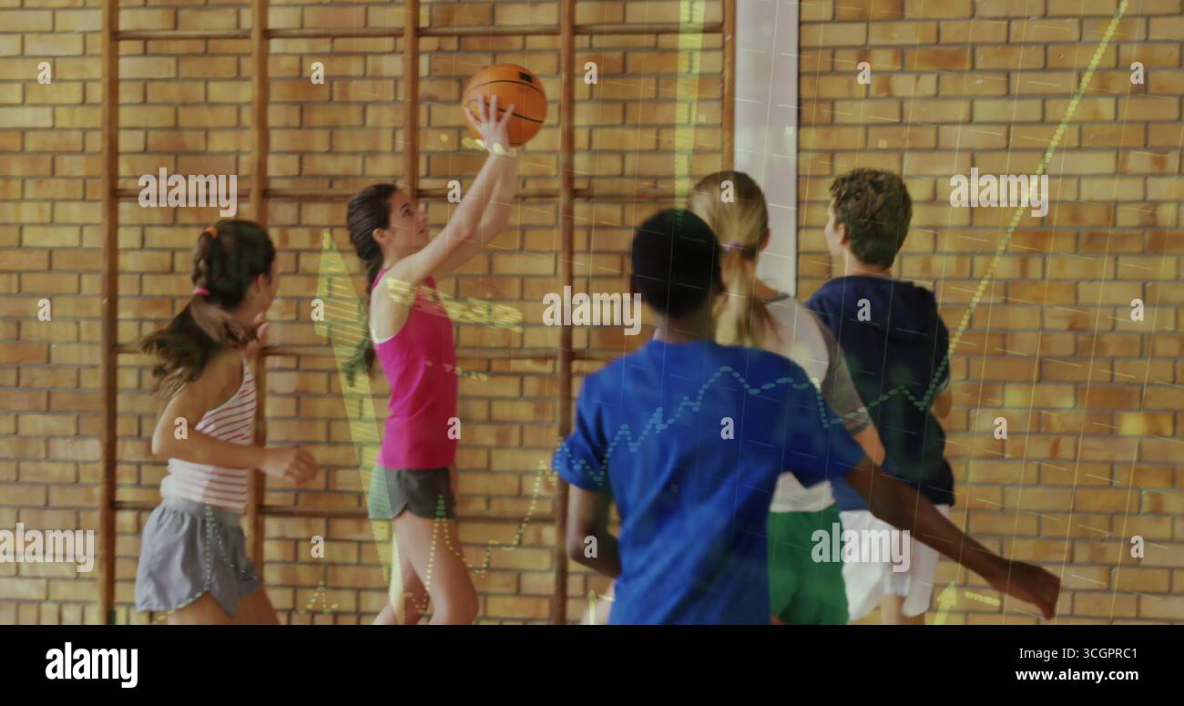 Ragazza che indossa la maglia rosa, pantaloncini grigi che sparano a basket nella palestra scolastica, con canestro e barre per arrampicata Foto Stock